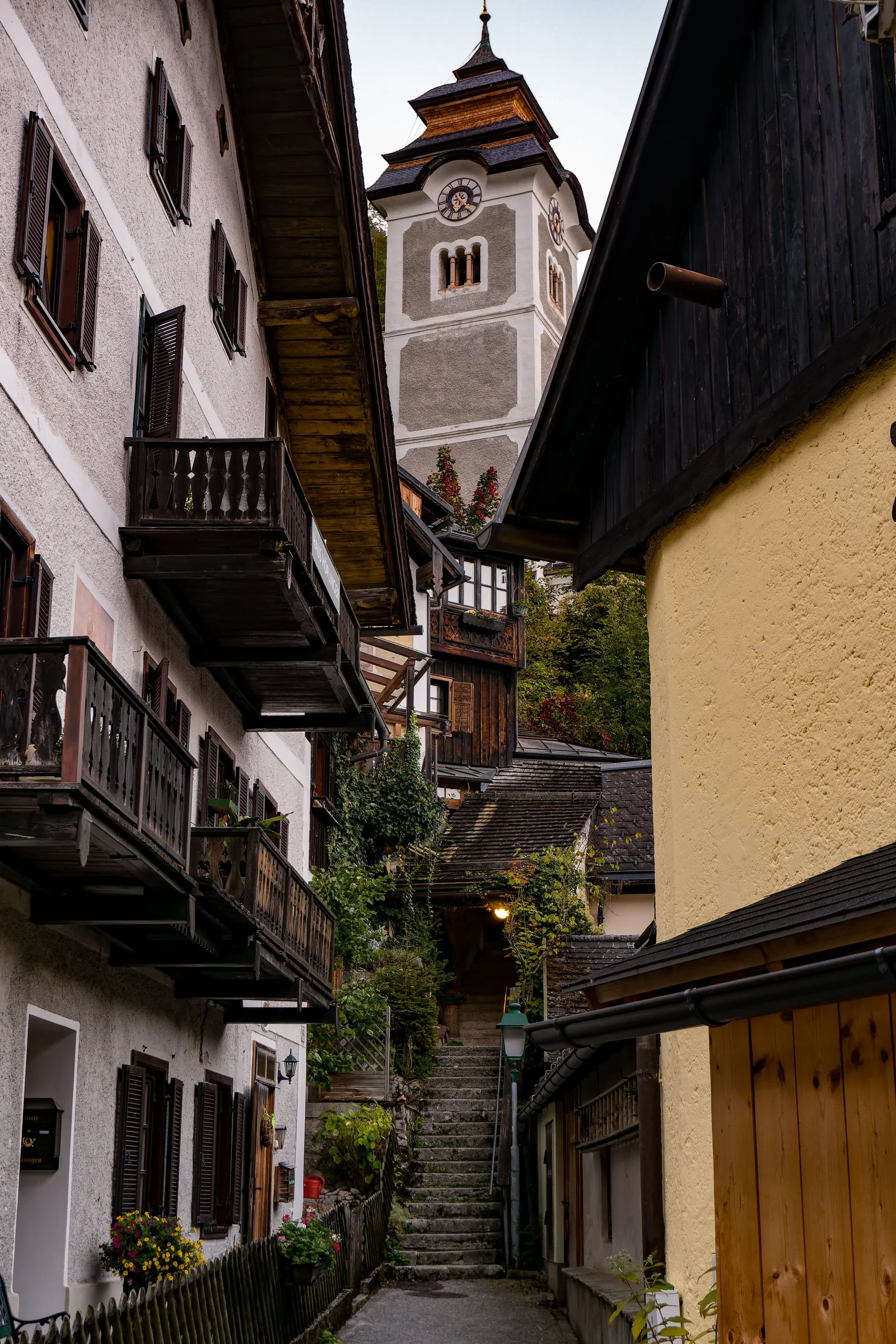 A narrow stepped path framed by wooden houses and a church tower