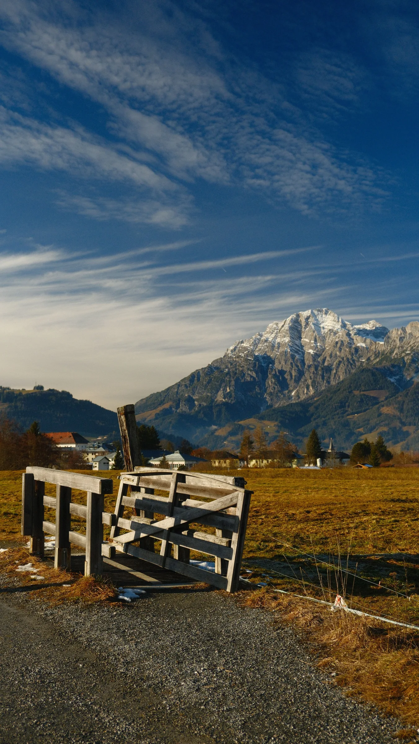 A wooden gate in a field with a mountain range extending behind it