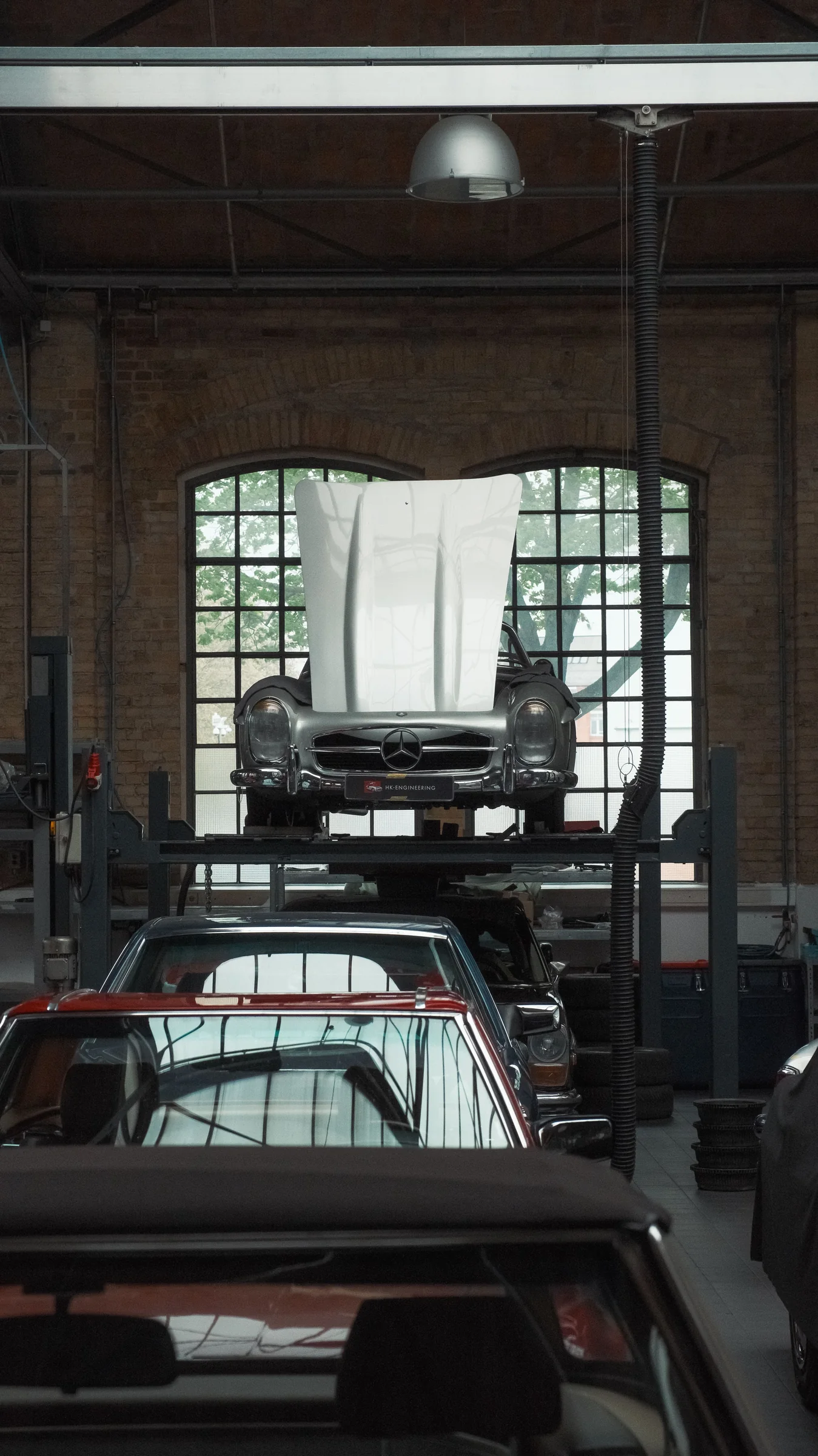 Classic Mercedes cars seen through the layered interior of a workshop