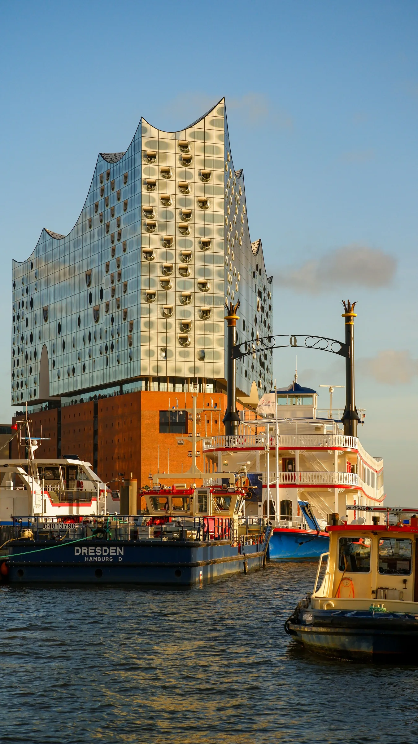 The Elbphilharmonie rising behind working boats in Hamburg harbour
