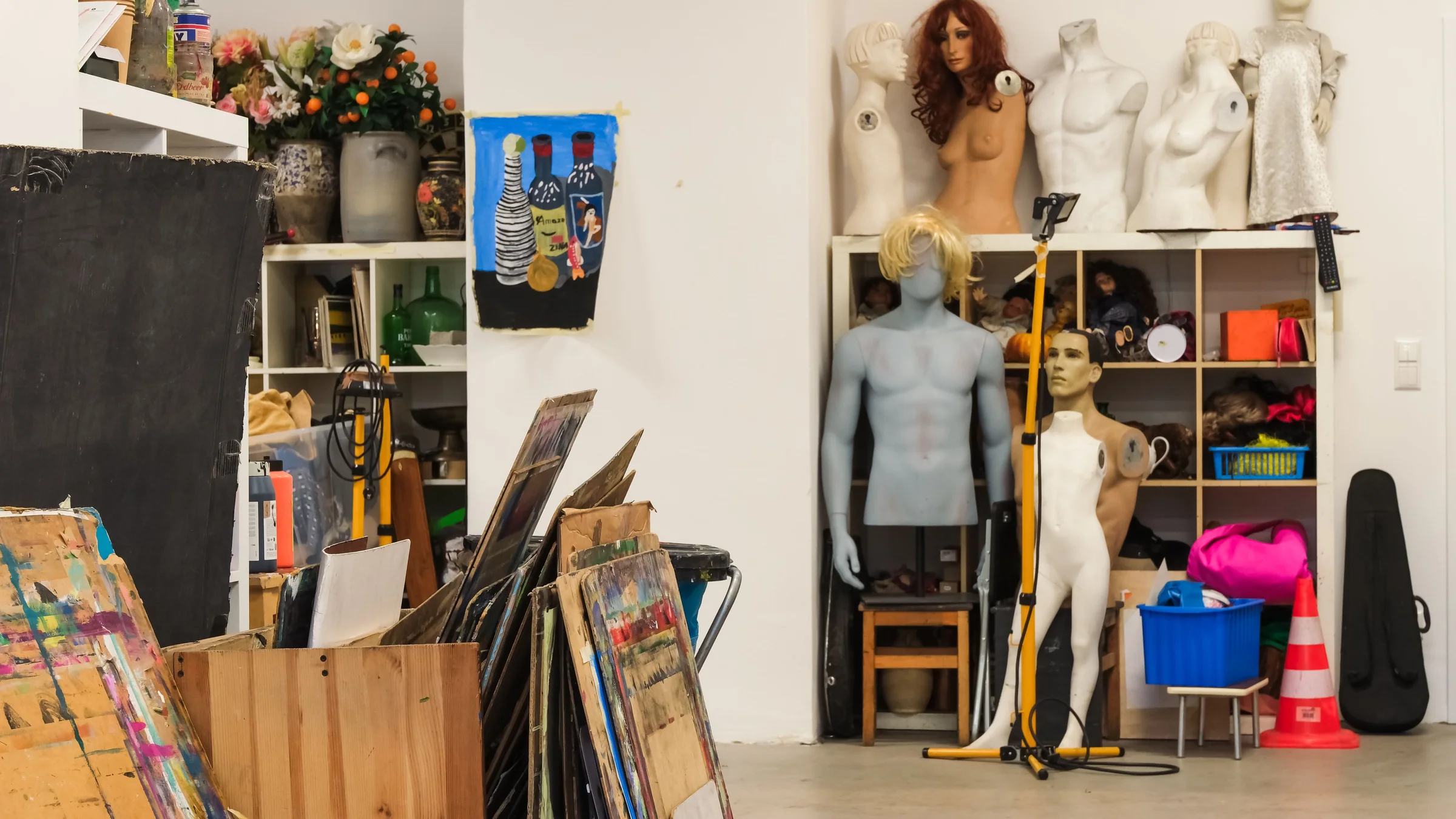 Mannequins, paintings and working materials arranged inside an artist's studio