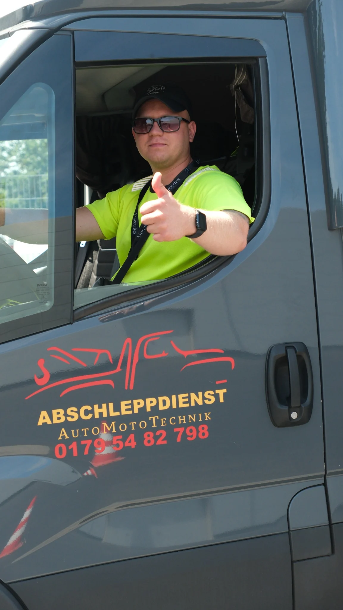 AutoMotoTechnik driver giving a thumbs-up from the truck cab