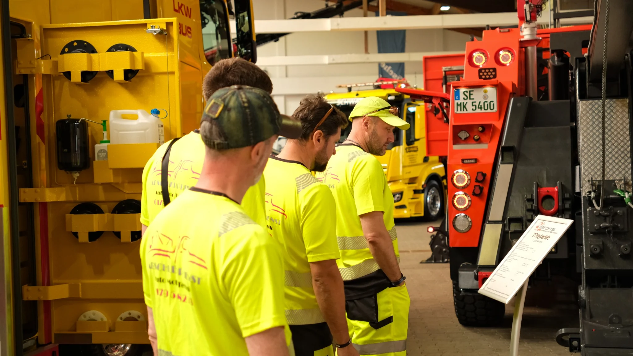 AutoMotoTechnik team examining heavy recovery equipment at a trade fair