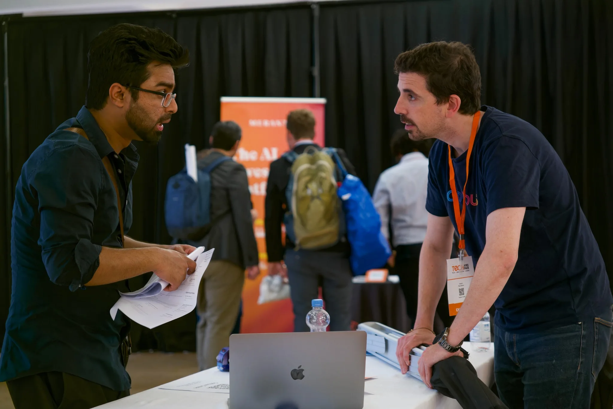 Two professionals in conversation at a technology job fair