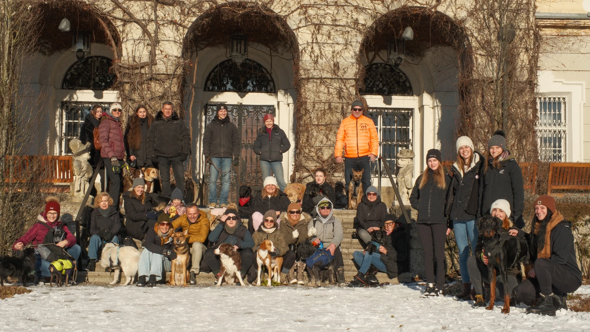 Group portrait of participants and dogs in front of a villa