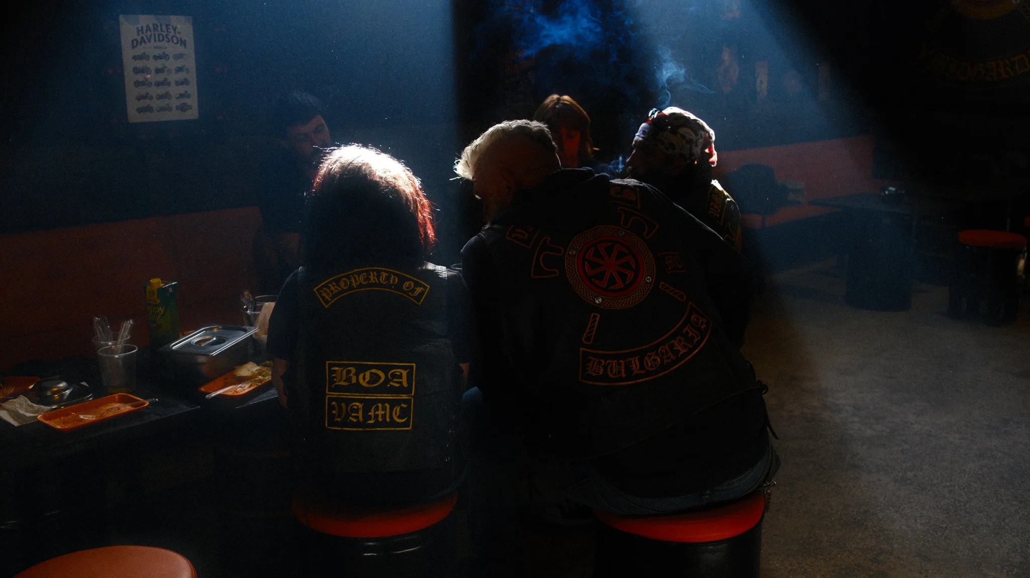Motorcycle club members gathered under dramatic beams of light