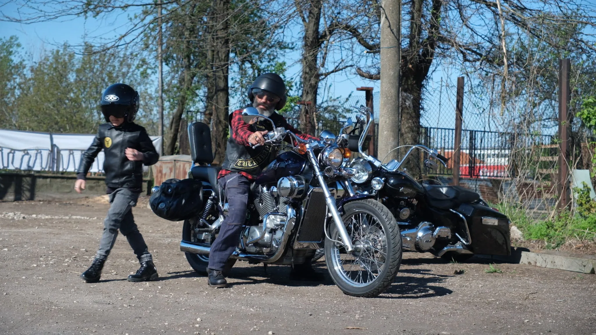 Motorcyclist on a cruiser with a child walking beside the bikes