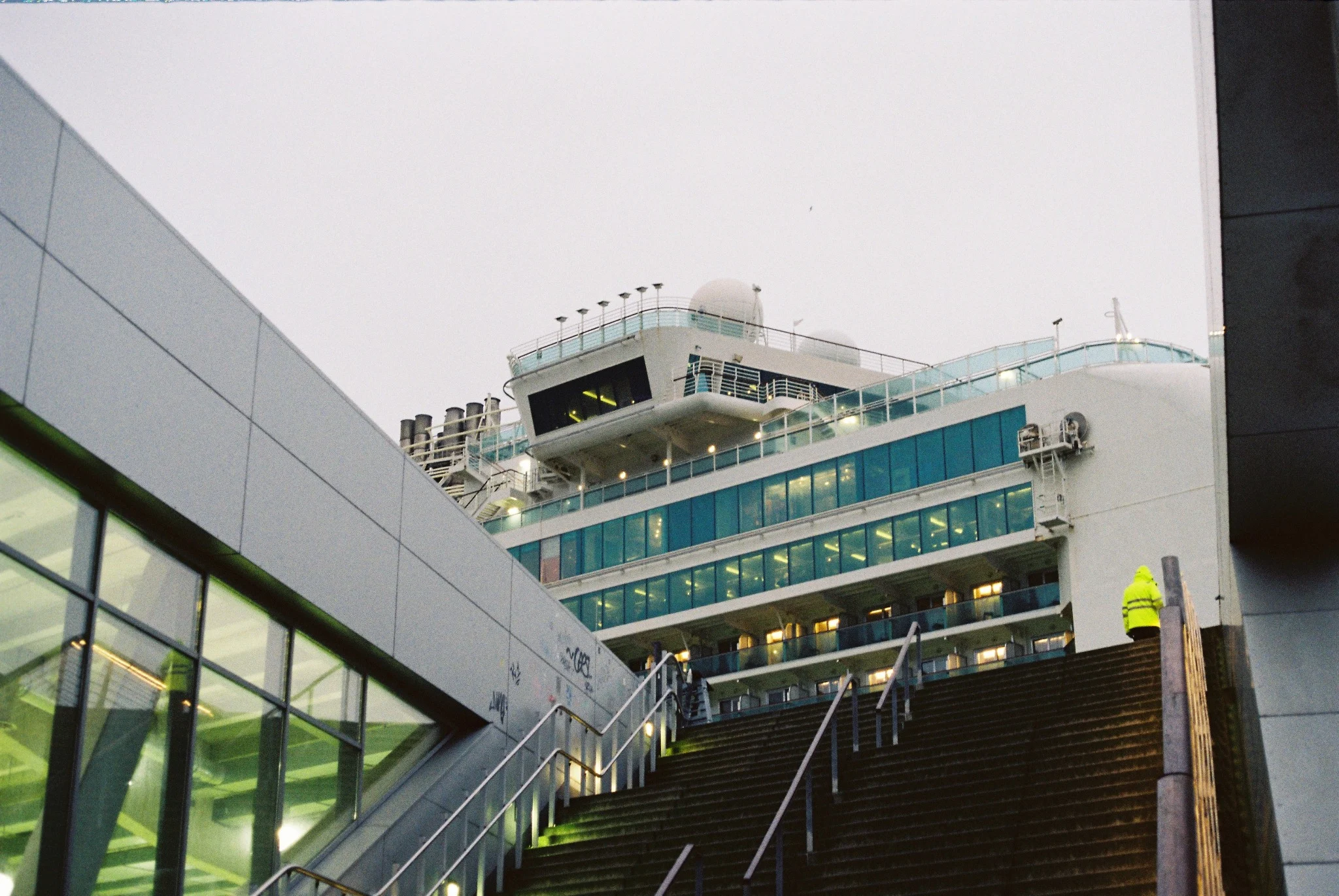 Industrial ferry terminal with a lone worker in a fluorescent jacket at the top of a staircase