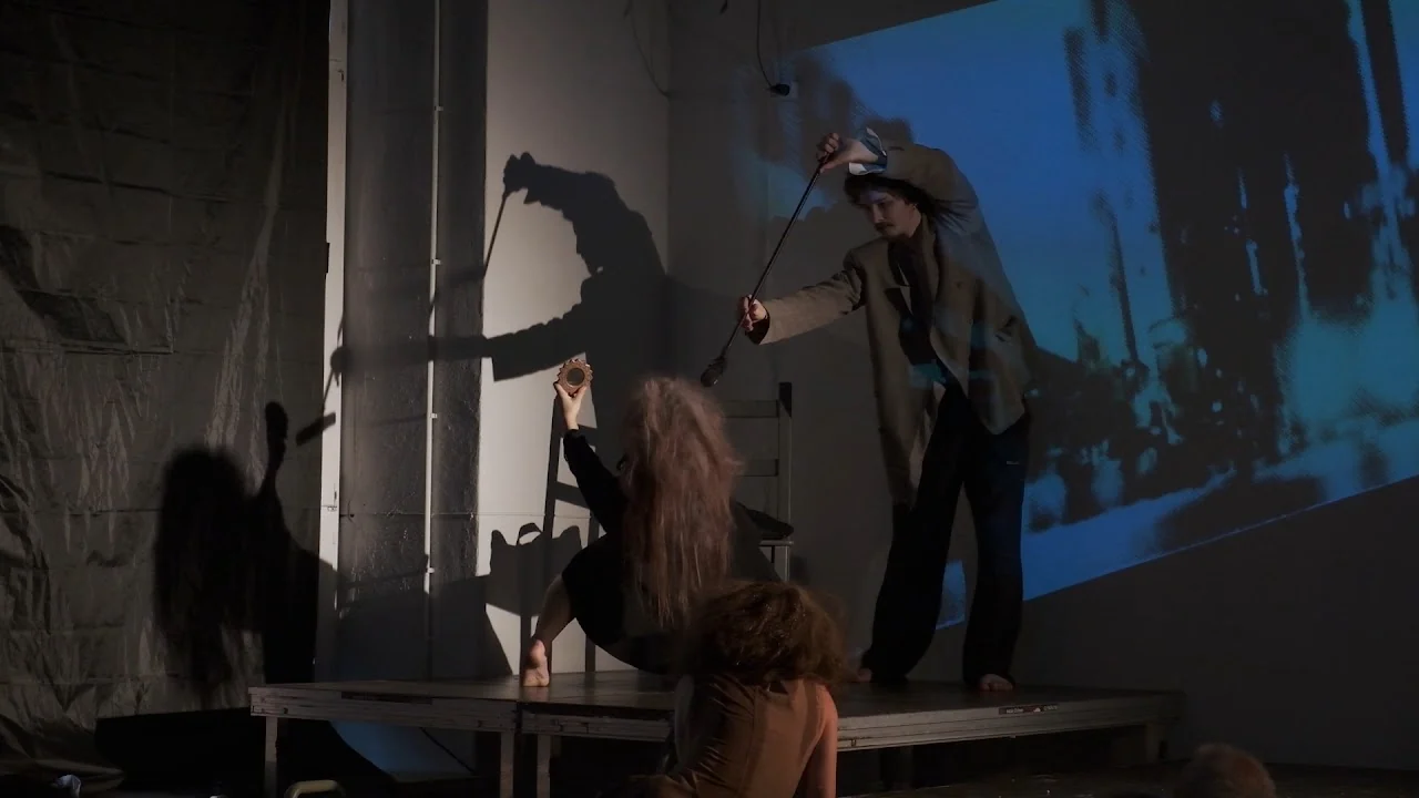 Performers interacting with objects and projected imagery on stage