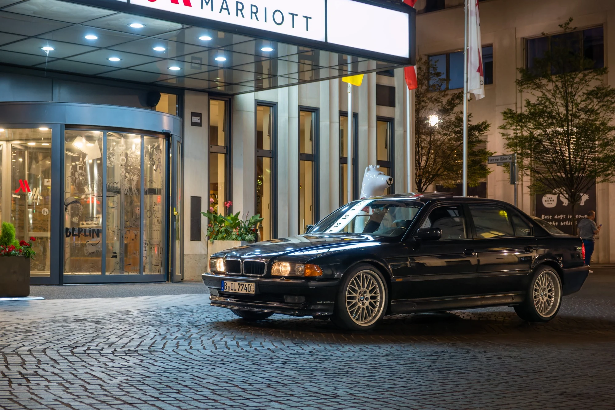 Black BMW 7 Series parked outside a Berlin Marriott hotel at night