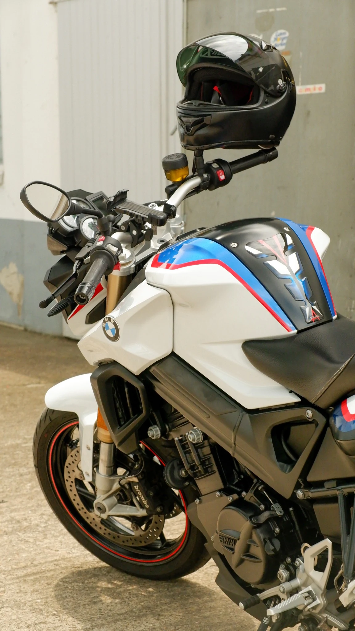 BMW motorcycle with M-style graphics and a helmet on the handlebar