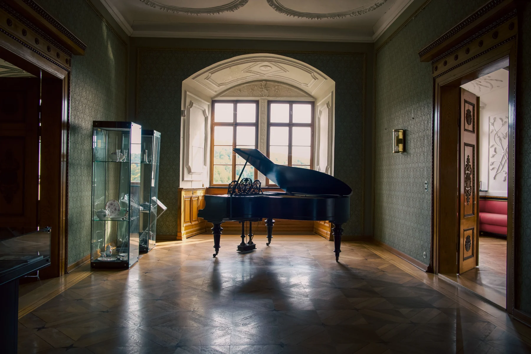 Grand piano illuminated by window light inside a historic castle room