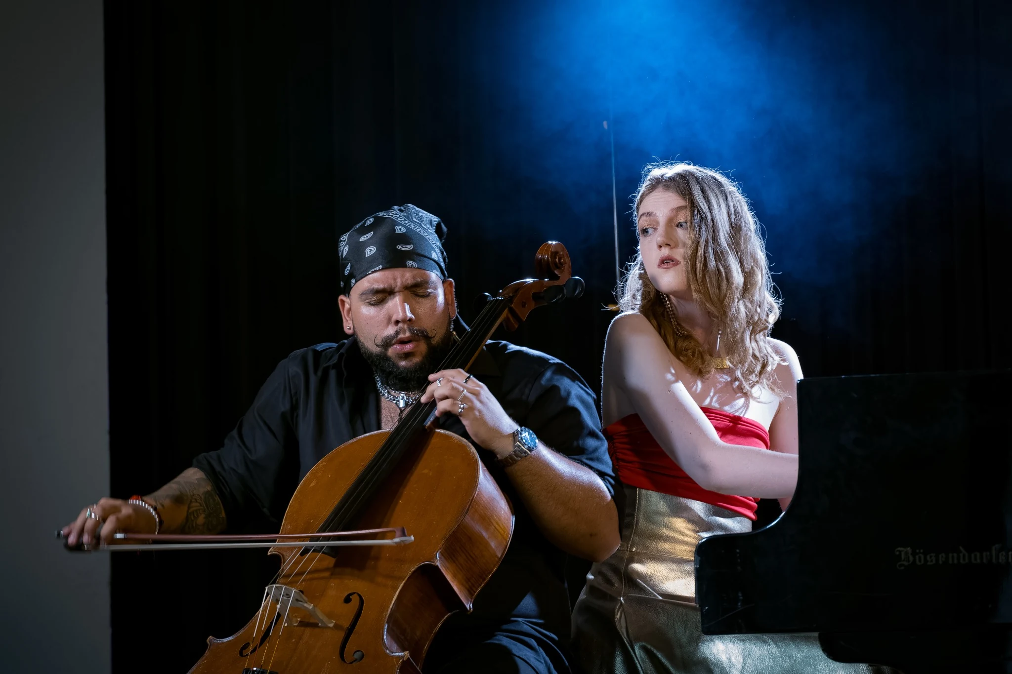 Cellist performing beside a pianist in atmospheric stage light