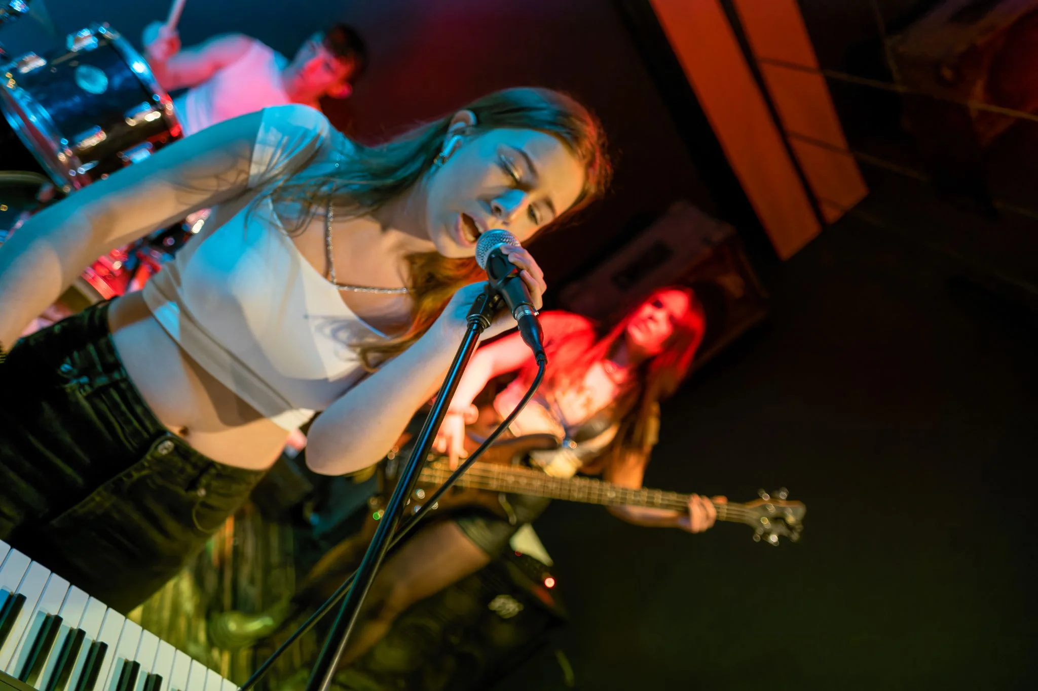 Singer performing with a band under vivid red and blue stage light