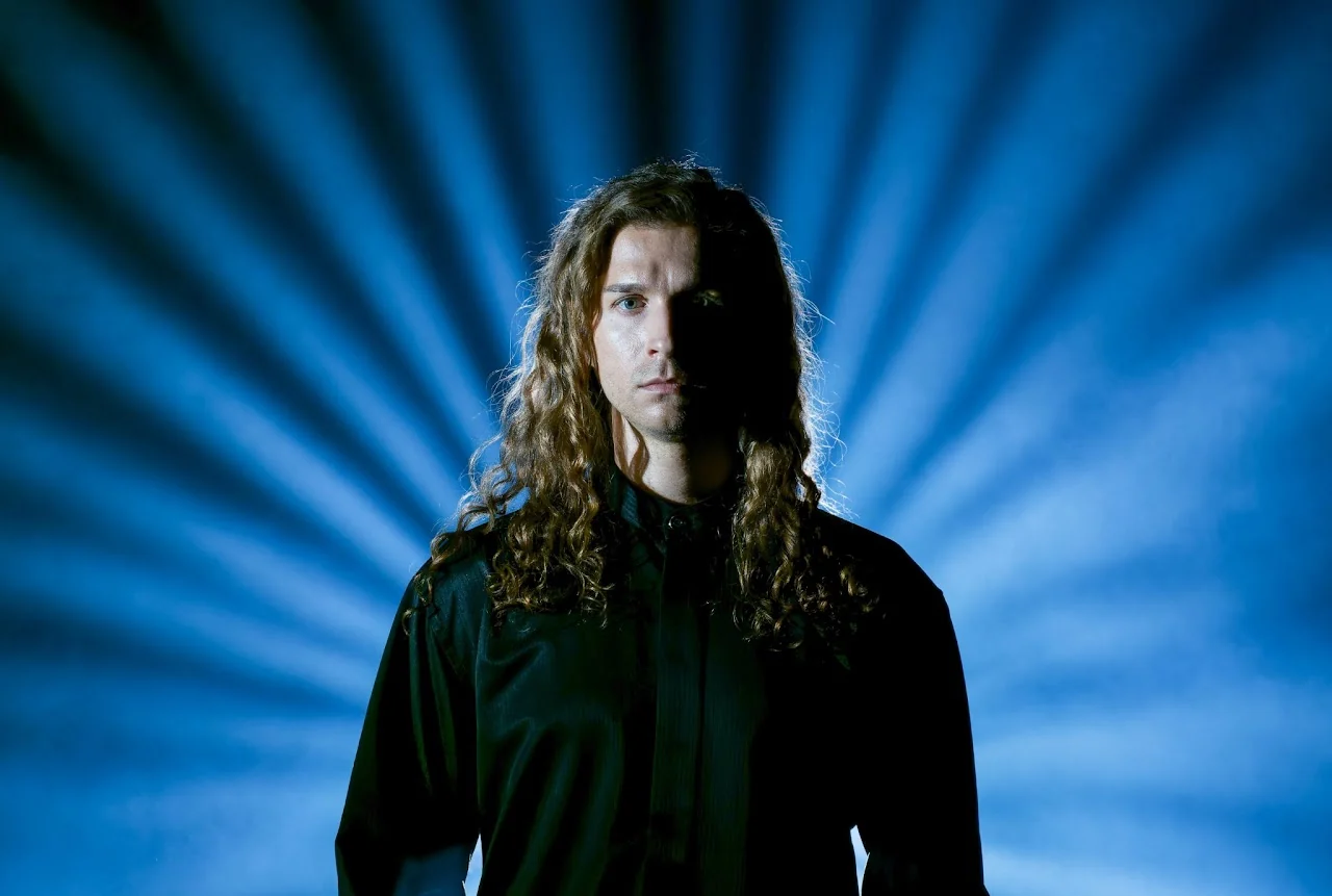 Portrait of a long-haired musician against dramatic blue light rays